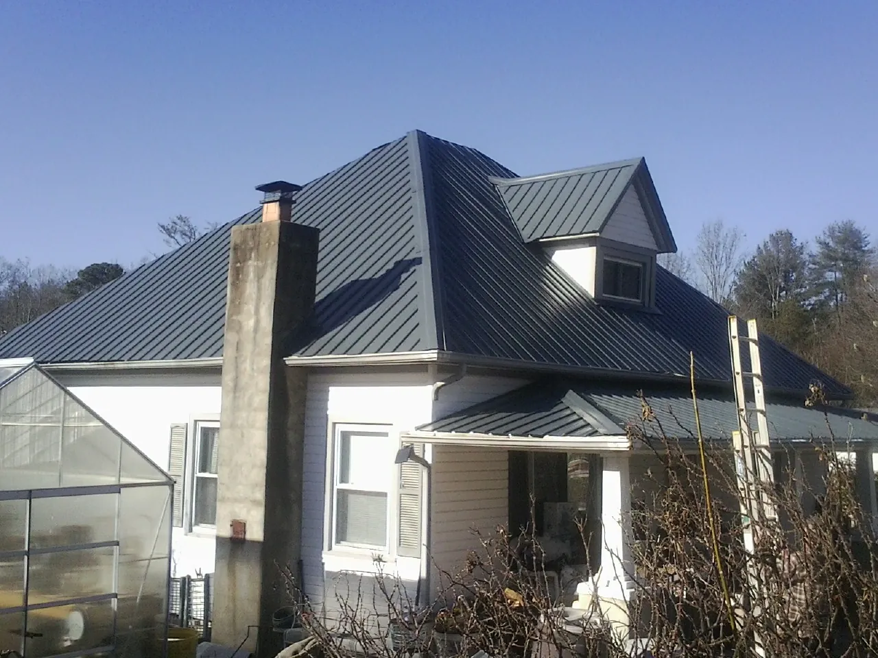 Dark blue standing seam metal roof on a white farmhouse with dormer — Slate & Tile Roof Repair by Roofing Brothers in Kunkletown