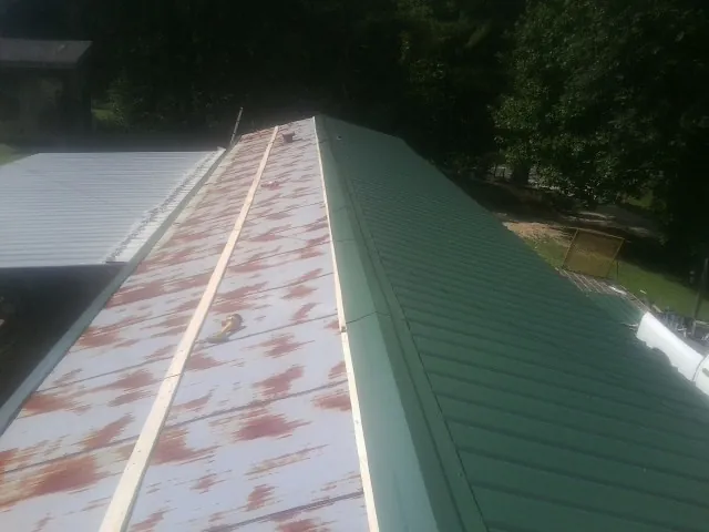 Old rusted panels beside newly installed green metal roofing — Wind Damage Roof Repair by Roofing Brothers in Kunkletown