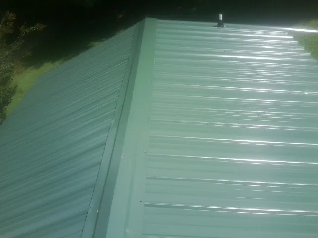 New green metal panels meeting at the ridge of a roof — Flat Roof Repair work by our crew in Kunkletown