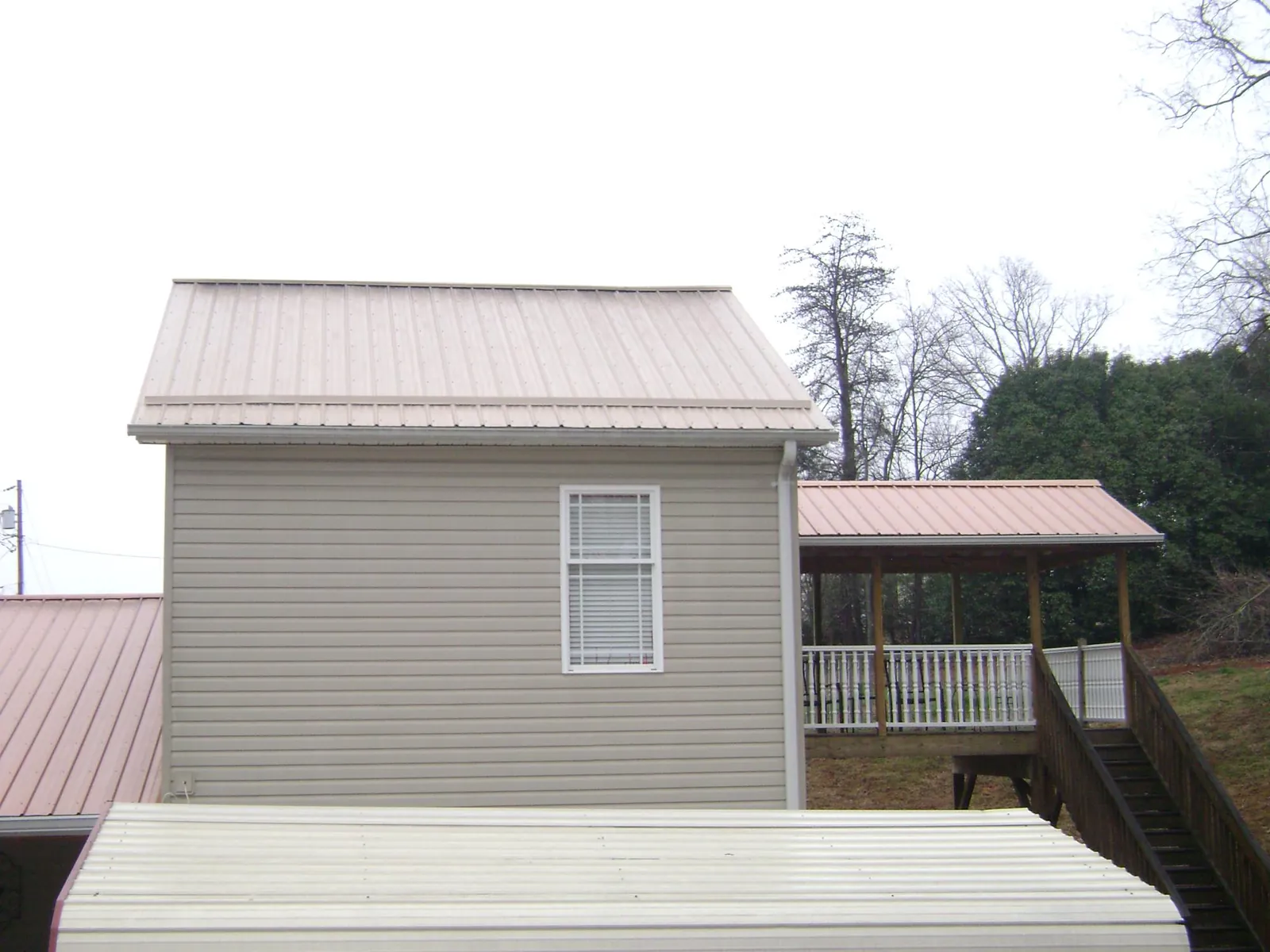 Tan metal roofs on a two story addition and attached porch, from a Roof Replacement job in Kunkletown