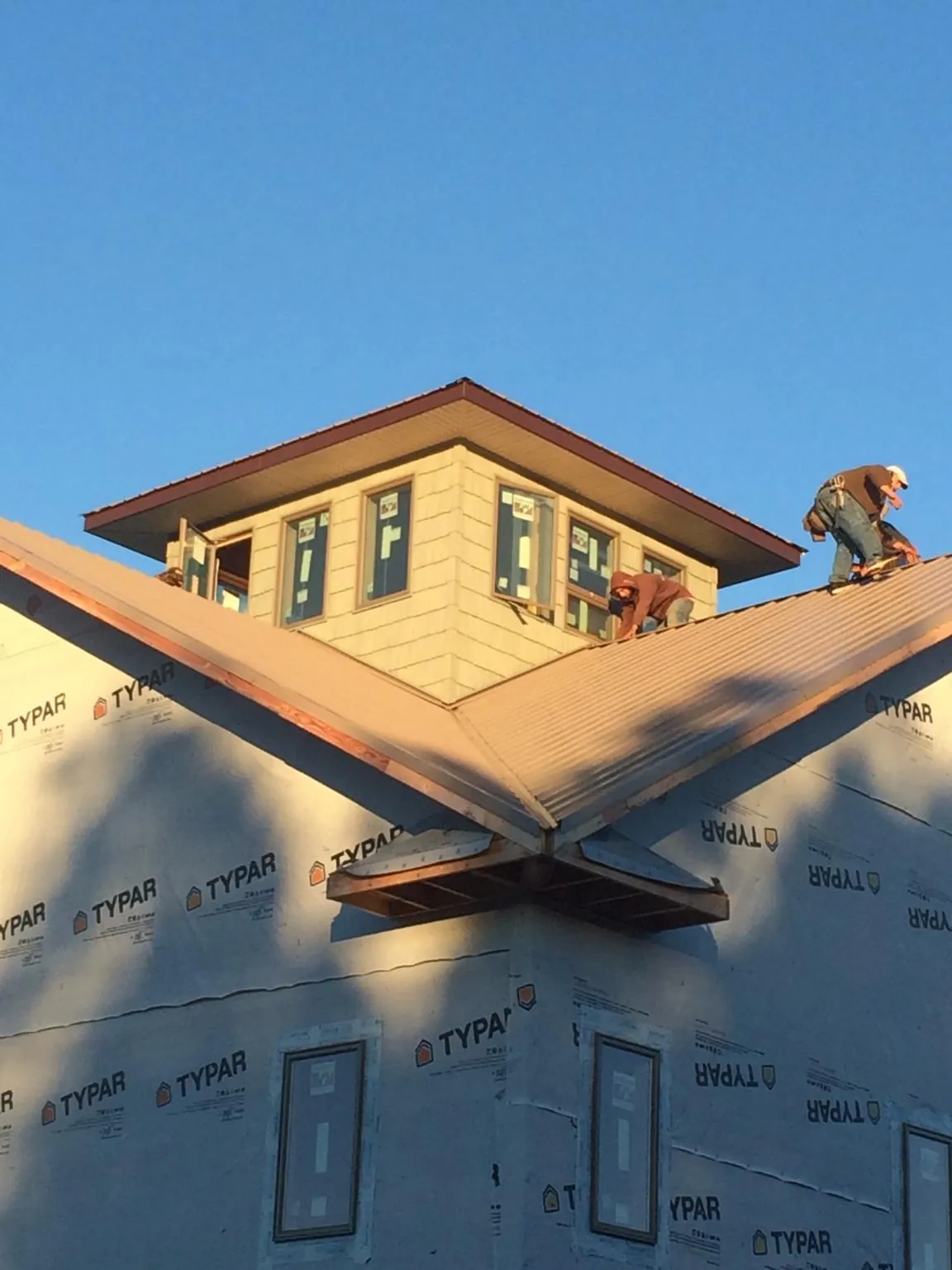 Roofers working around a rooftop cupola on a new metal roof at sunset — Roof Waterproofing in Kunkletown by Roofing Brothers